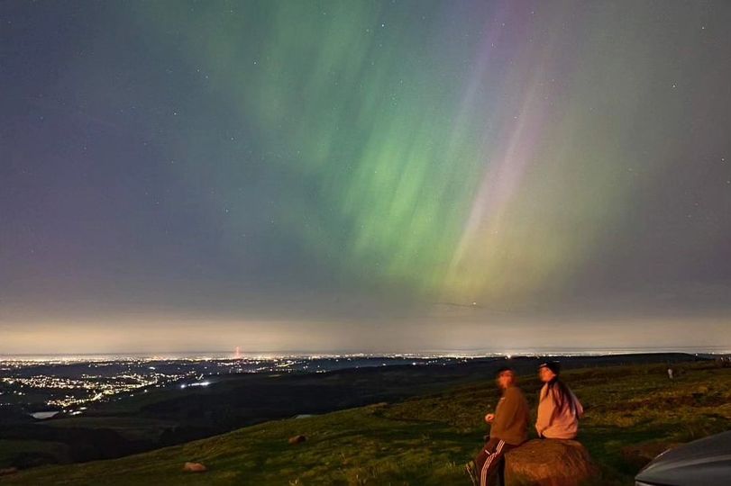 2 children looking at a panorama of a city with aurora sky